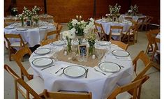 the table is set with white flowers and place settings for two people to sit at