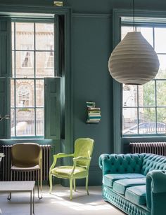 a living room filled with green furniture and lots of window sills on the walls