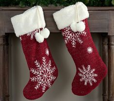 two red and white christmas stockings hanging from a mantel with snowflakes on them