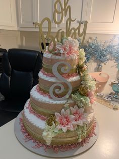 a three tiered cake with pink flowers and gold numbers on top sits on a table