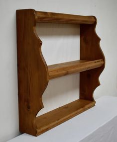 a wooden shelf sitting on top of a white tablecloth covered table next to a wall