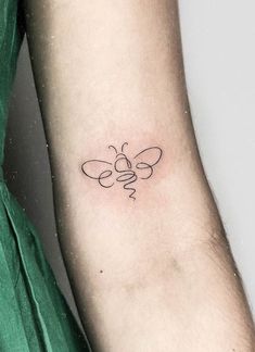 a small tattoo on the arm of a woman's left arm with a bee