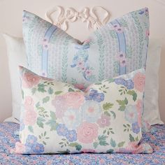 two decorative pillows on a bed with flowers