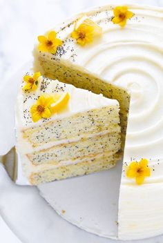 there is a cake with white frosting and yellow flowers on the top it has one slice cut out