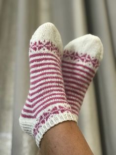 a person wearing striped socks with their feet up on a metal surface in the background