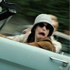 a woman driving in the back seat of a car with her head out the window