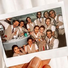 a person holding up a polaroid photo of some people in uniform and smiling at the camera