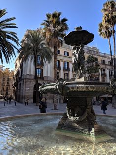 a fountain in the middle of a plaza with palm trees