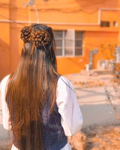 a woman with long hair standing in front of an orange building