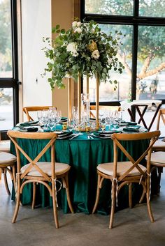 the table is set with green linens and white flowers in a tall centerpiece