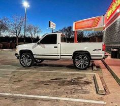 a white pickup truck parked in a parking lot next to a gas station sign at night