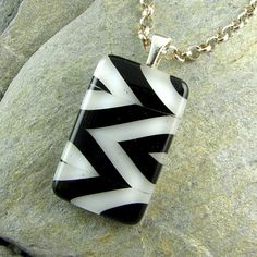 a black and white glass pendant sitting on top of a rock