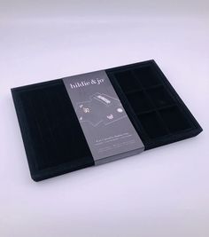 the inside of a black box with two compartments for earrings and earring sets on it