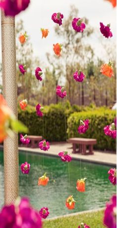 an instagram photo with pink and orange flowers hanging from it's pole next to a pool