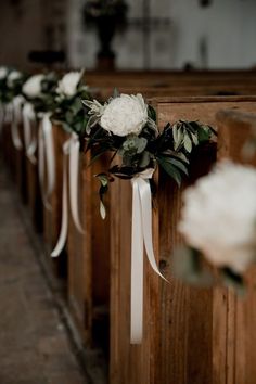 white flowers and greenery are tied to the pews