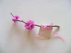 pink flowers are tied to a twig on a white surface