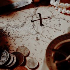 a cross on top of a map surrounded by coins and other things that are around it