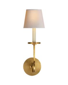 a gold wall light with a white shade on the side and a small lamp in front of it