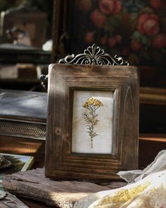 an old frame with a flower in it on top of a table next to other items