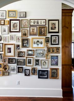 a wall with many framed pictures on it