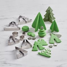 christmas cookies and cookie cutters on a marble counter top with trees, snowflakes and stars