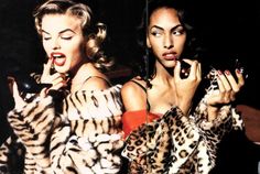 two women dressed in animal print clothing holding cell phones and pointing at the camera with their mouths open