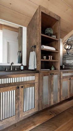 a bathroom with wooden cabinets and white towels on the counter top, along with wood flooring