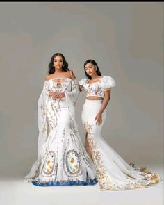 two women in white dresses standing next to each other