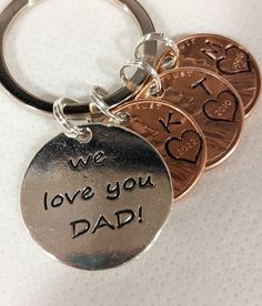 three different coins with the words we love you dad written on them are shown in this keychain