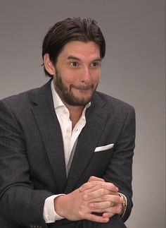 a man in a suit sitting down with his arms crossed