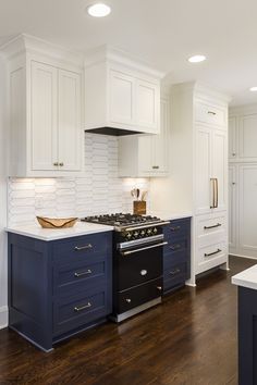 a kitchen with white cabinets and blue counter tops, wood flooring and an island in the middle