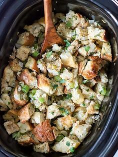 a crock pot filled with stuffing and a wooden spoon