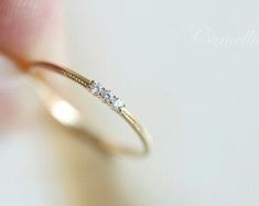 a woman's hand holding a gold ring with three diamonds on top of it