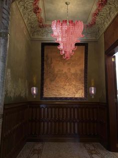 a pink chandelier hanging from the ceiling in a room with wood paneling