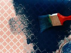 a red paint brush sitting on top of a blue floor