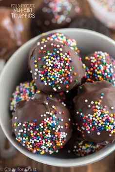 chocolate covered donuts with sprinkles in a white bowl on a wooden table