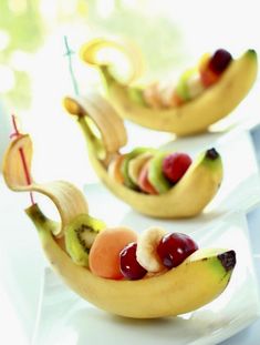 some fruit shaped like banana boats on a white plate