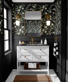 a bathroom with black and white wallpaper, gold fixtures and a floral design on the wall