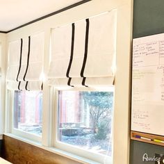 a kitchen window covered in black and white roman blind blinds with writing on the windowsill