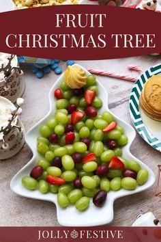 a christmas tree made out of grapes on a table with cookies and other desserts