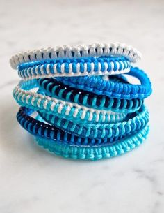 several blue and white bracelets stacked on top of each other in front of a marble surface