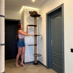 a woman standing in front of a cat tree