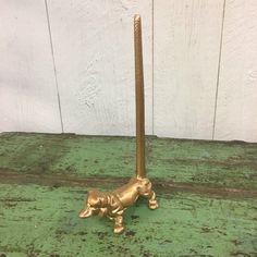 a brass dog figurine sitting on top of an old green table next to a white wall