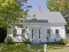 a white house sitting in the middle of a lush green yard