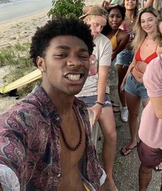 a group of young people standing next to each other on a sidewalk near the ocean