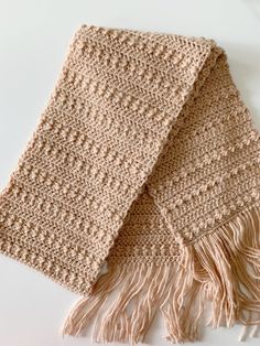 two crocheted scarfs on a white surface with one folded over the other