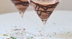 two glasses filled with ice cream and sprinkles on a white tablecloth