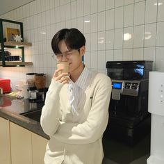 a woman standing in a kitchen drinking from a cup