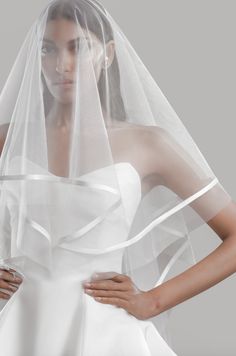 a woman wearing a wedding veil with her hands on her hips