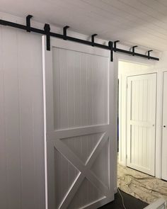 an open barn door in a room with white walls and black hardware on the doors